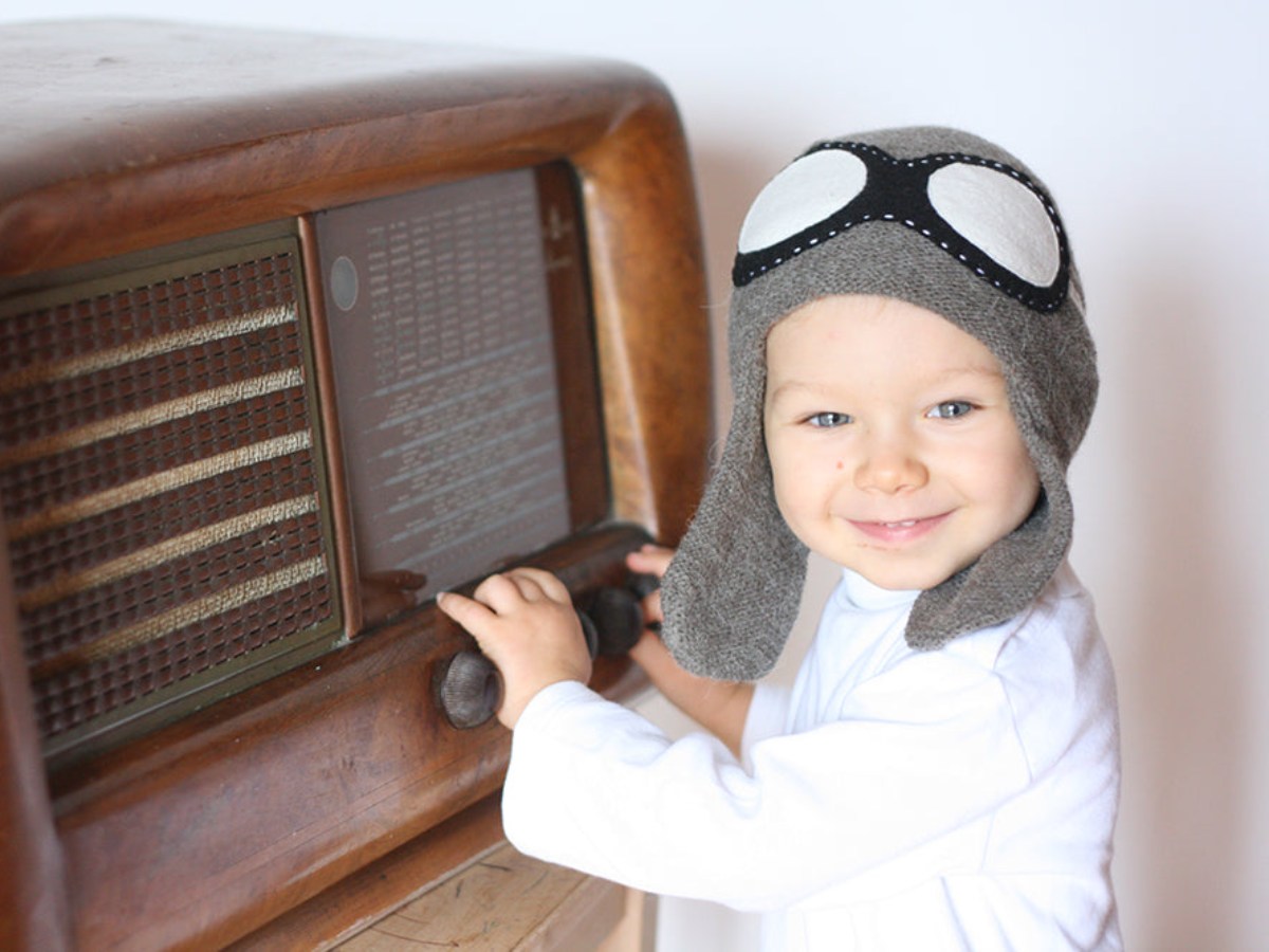 bambino con il cappello grigio da aviatore sta giocando con la vecchia radio
